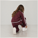 victor and jane girls maroon fleece sweatshirt and jogger set with white side stripes worn by a girl kneeling