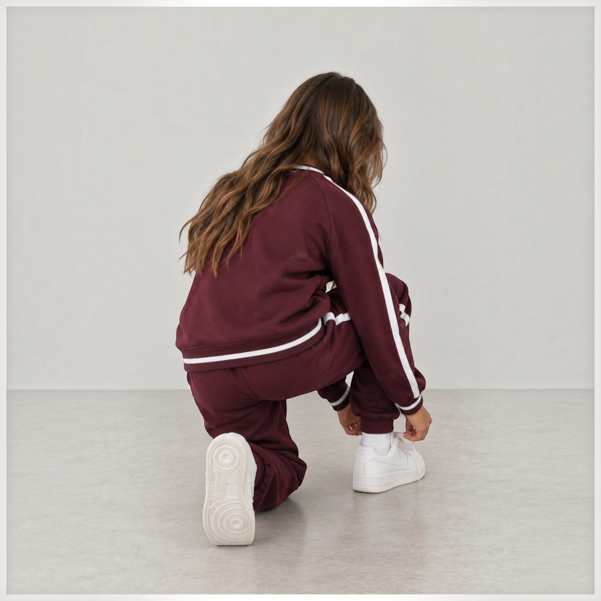 victor and jane girls maroon fleece sweatshirt and jogger set with white side stripes worn by a girl kneeling