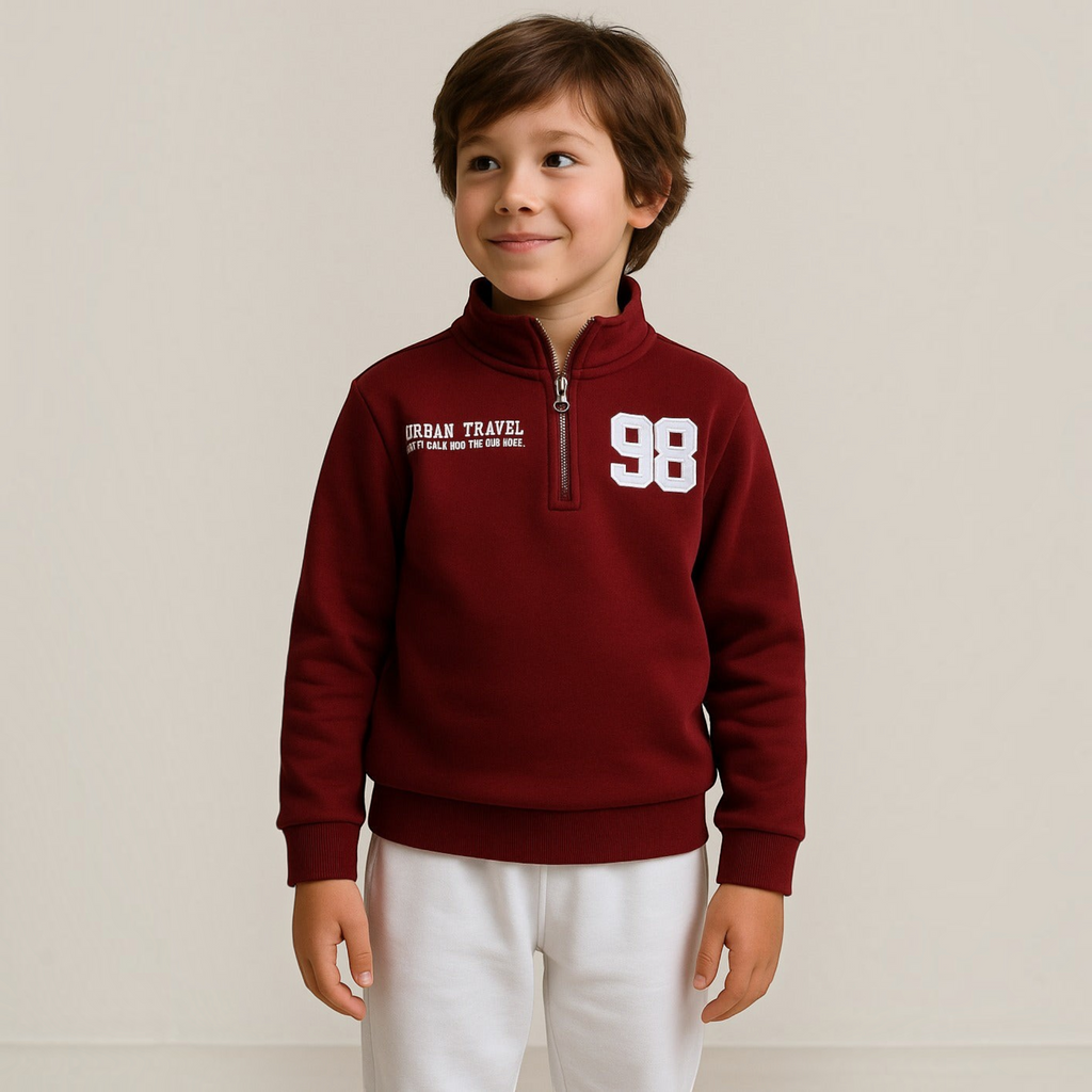 Young boy wearing a victor and jane burgundy quarter-zip sweatshirt with white Urban Travel and 98 graphic prints.