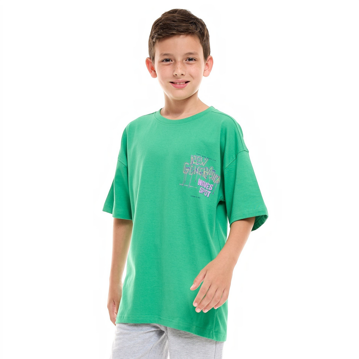 A young boy wearing a green victor and jane graphic t-shirt with New Generation text print on a white background