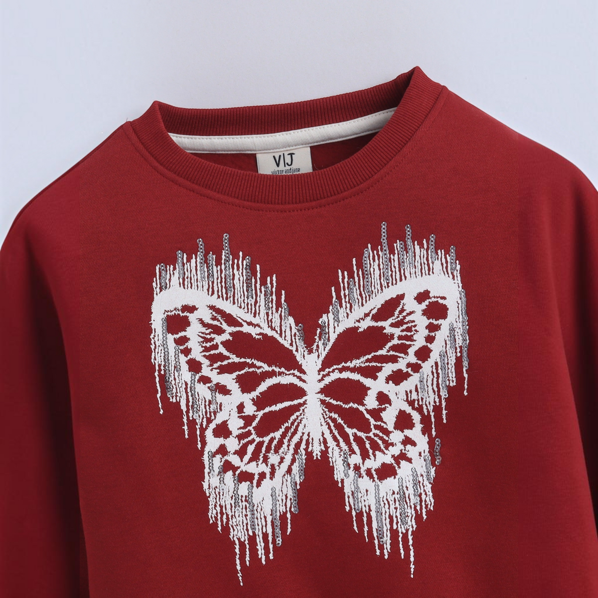 victor and jane girls red sweatshirt featuring a white butterfly graphic with a distressed fringe effect