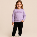 Young girl wearing a victor and jane light purple sweatshirt with floral text detail and black joggers