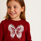Young girl wearing a deep red victor and jane sweatshirt featuring a white distressed butterfly graphic print