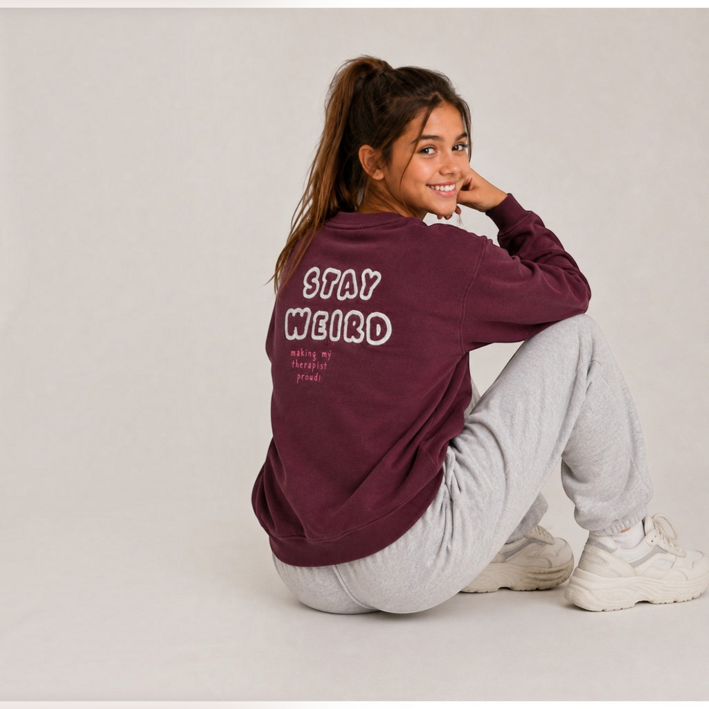 victor and jane girls burgundy fleece pullover with Stay Weird graphic print on the back worn by a smiling girl
