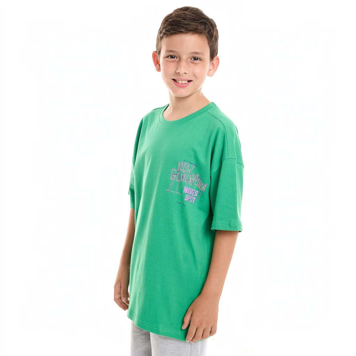 A young boy wearing a green victor and jane graphic t-shirt with New Generation Waves Spot print on the chest.