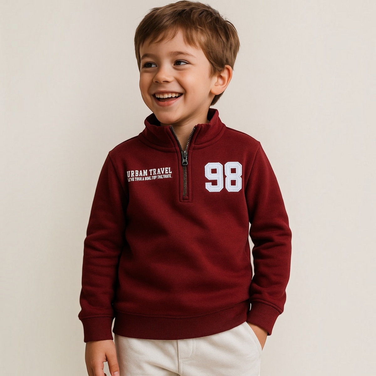 A young boy wearing a burgundy victor and jane Boys Texas Zip quarter-zip sweatshirt with white graphic text.