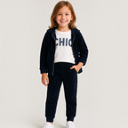 A young girl wearing a victor and jane navy glitter hoodie, white graphic t-shirt, and matching jogger pants set.