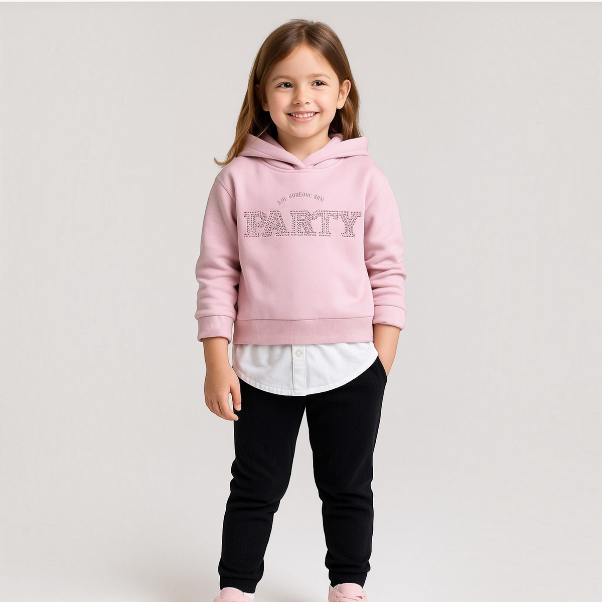 Young girl wearing a victor and jane light pink hoodie with rhinestone PARTY text and a white shirt hem layer