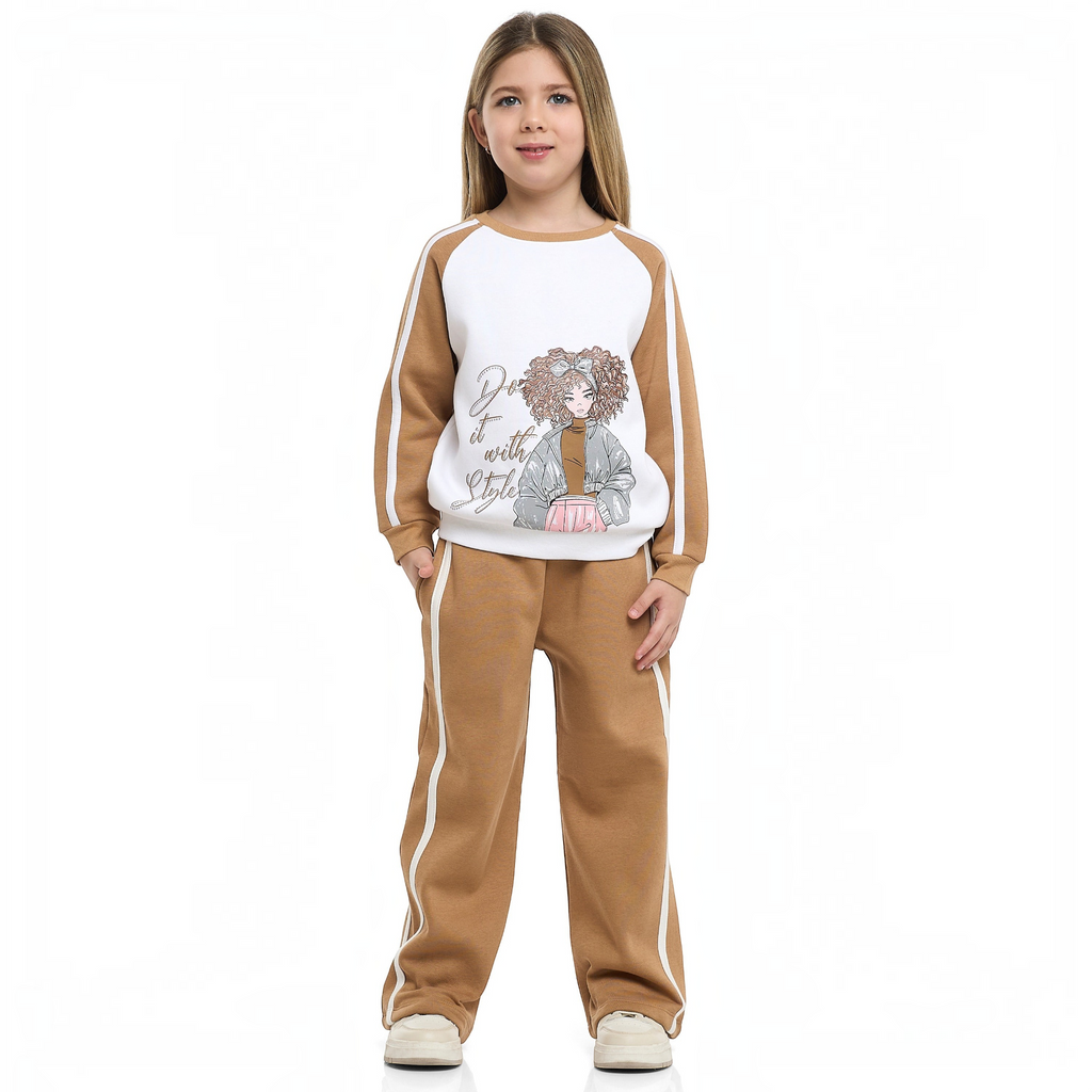 Young girl wearing a victor and jane two-piece tan and white tracksuit with a graphic print sweatshirt