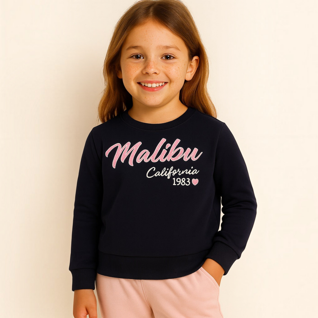 Young girl wearing a navy blue victor and jane sweatshirt with pink Malibu California 1983 graphic print