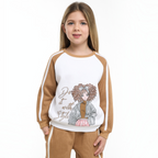 Young girl wearing a victor and jane two-piece set with a white and tan graphic sweatshirt and matching tan joggers.