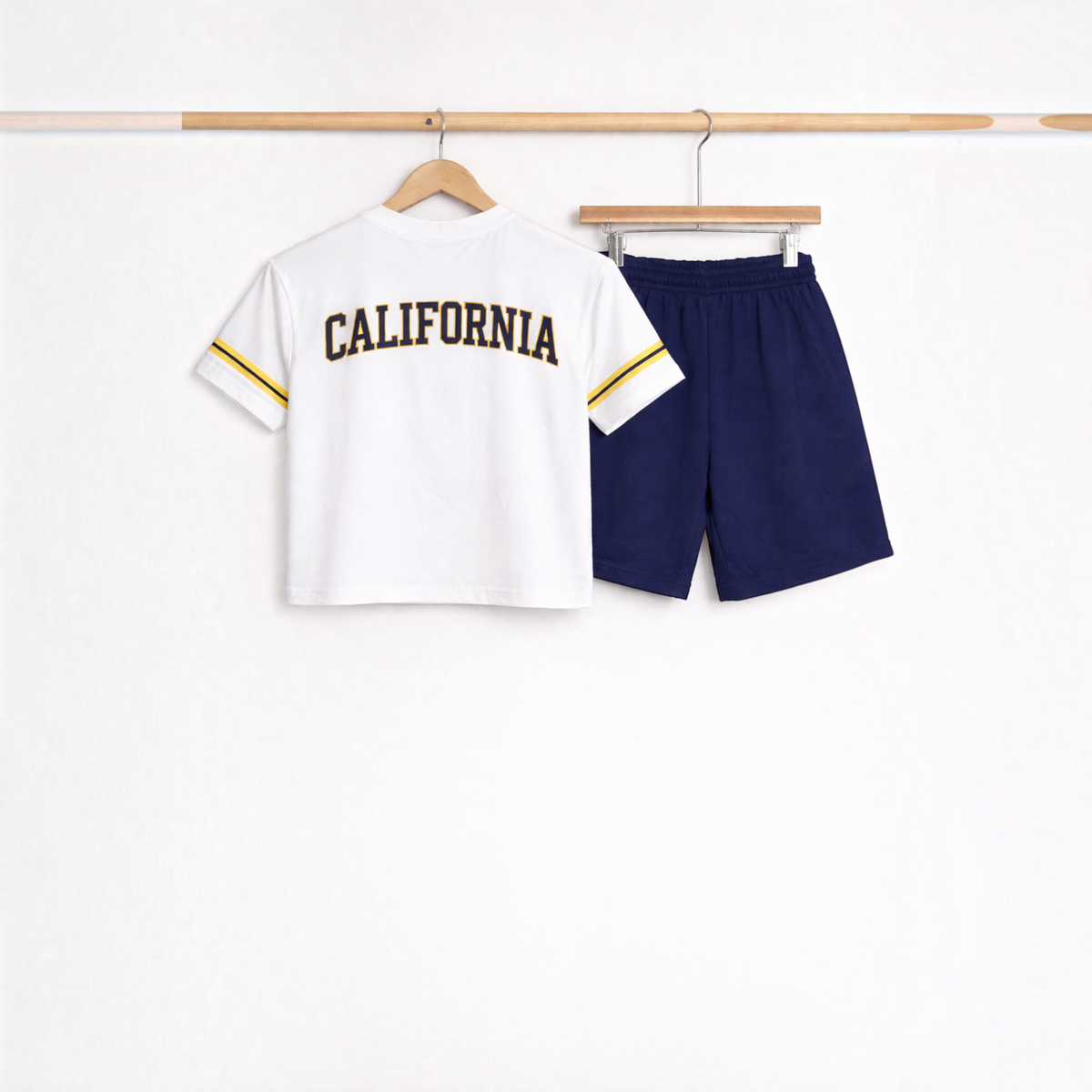 victor and jane boys white t-shirt with California print and navy blue shorts set hanging on wooden hangers