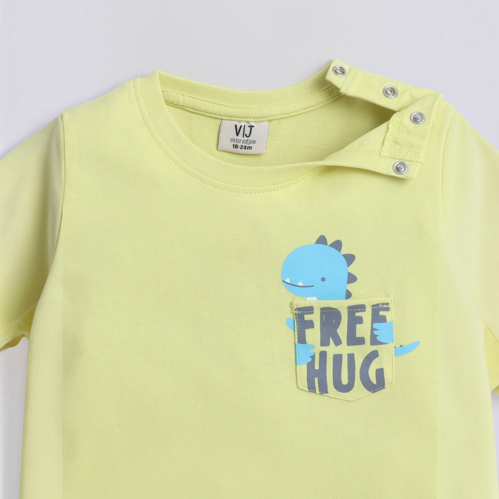 victor and jane boys light yellow t-shirt with a blue dinosaur graphic on the pocket and shoulder snap buttons