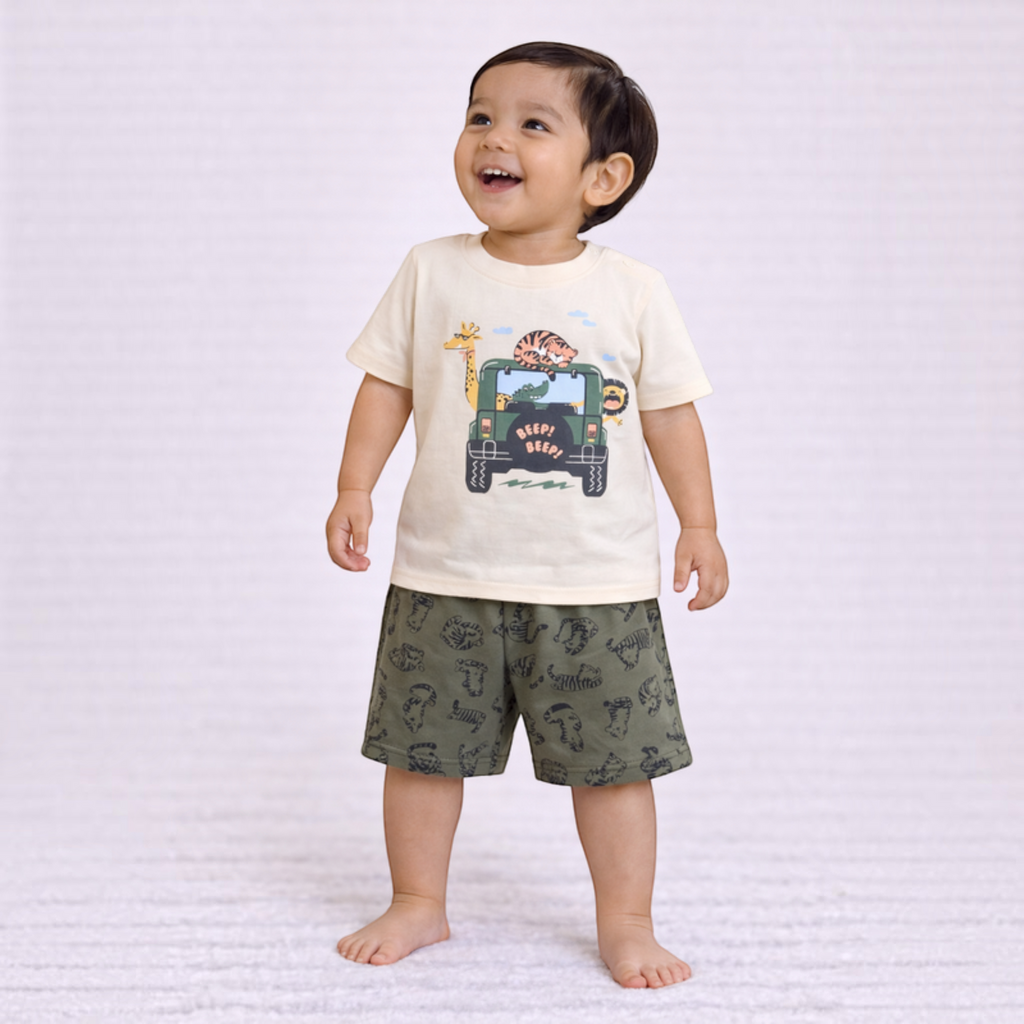 A toddler boy wearing a victor and jane cream t-shirt with a safari jeep print and olive green animal print shorts.
