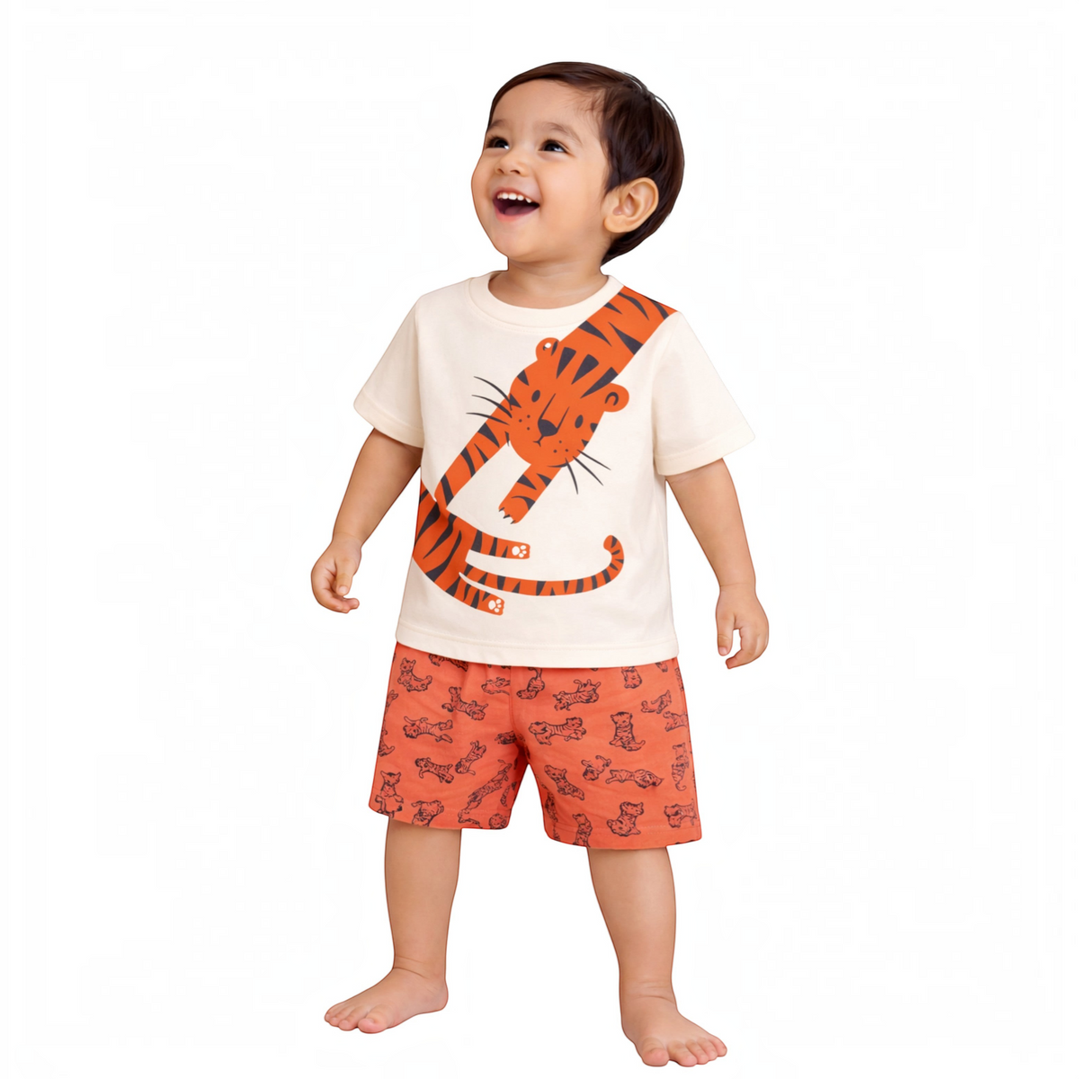 A happy toddler boy wearing a victor and jane cream t-shirt with a tiger print and matching orange tiger shorts.
