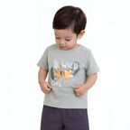 A toddler boy wearing a sage green victor and jane t-shirt with a Wild One tiger graphic and dark grey shorts.
