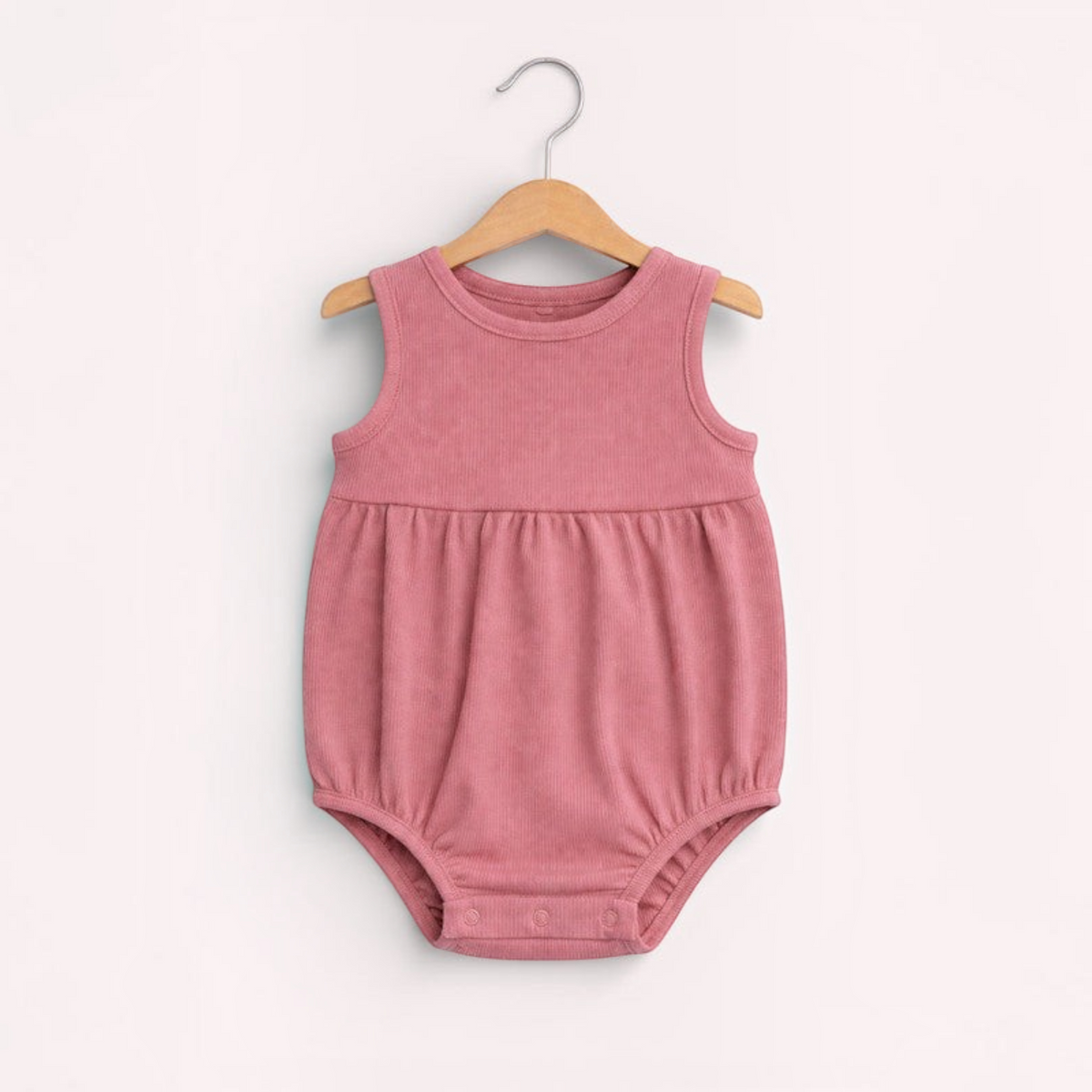 victor and jane baby girls sleeveless ribbed romper in a dusty rose pink colour hanging on a wooden hanger