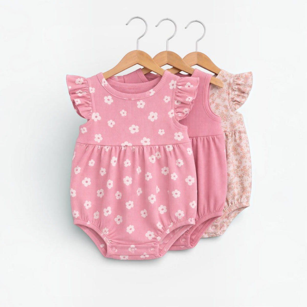 victor and jane baby girls floral rompers in pink and white with flutter sleeves on wooden hangers