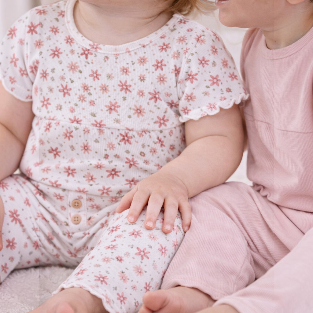 Two toddlers wearing victor and jane matching ribbed cotton shirt sets in floral print and solid light pink