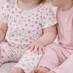 Two toddlers wearing victor and jane matching ribbed cotton shirt sets in floral print and solid light pink