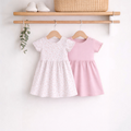 victor and jane baby girls 2-piece dress set featuring a floral print dress and a solid pink dress on wooden hangers