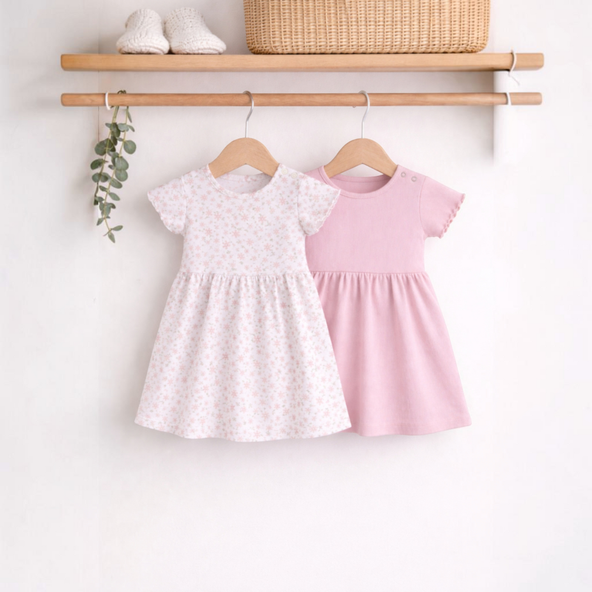 victor and jane baby girls 2-piece dress set featuring a floral print dress and a solid pink dress on wooden hangers