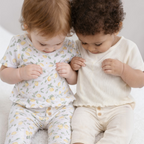 Two baby girls wearing victor and jane matching two-piece sets in lemon print and cream ribbed cotton