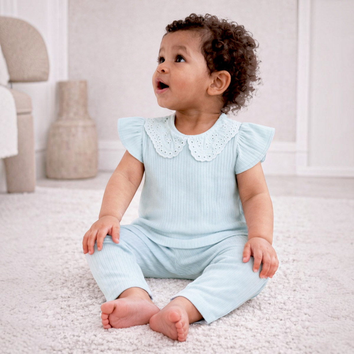 victor and jane baby girl wearing a light blue ribbed two-piece shirt set with a delicate eyelet lace collar