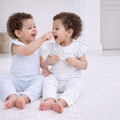 Two baby girls wearing victor and jane matching pastel floral and ribbed cotton shirt sets while playing together.