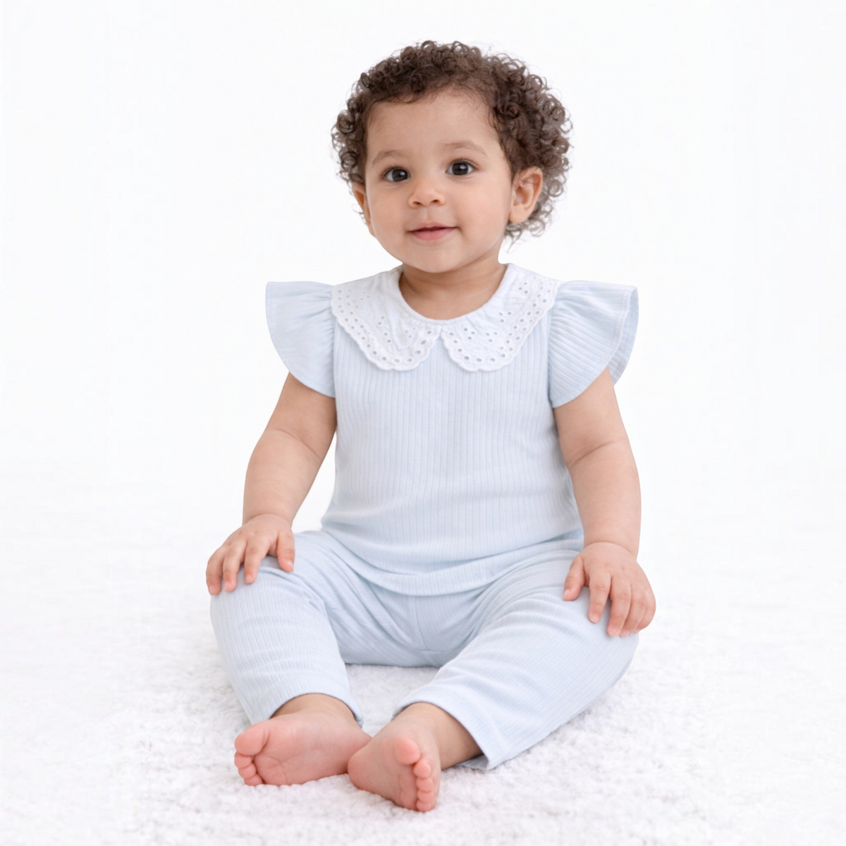 Baby girl wearing a victor and jane light blue ribbed two-piece shirt set with a white eyelet collar.