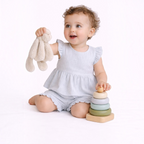 victor and jane baby girl wearing a light blue striped ruffled shorts set while playing with a wooden stacking toy