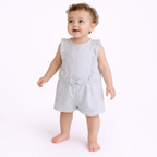 A baby girl wearing a light blue and white striped victor and jane romper with ruffled shoulders and a small bow.