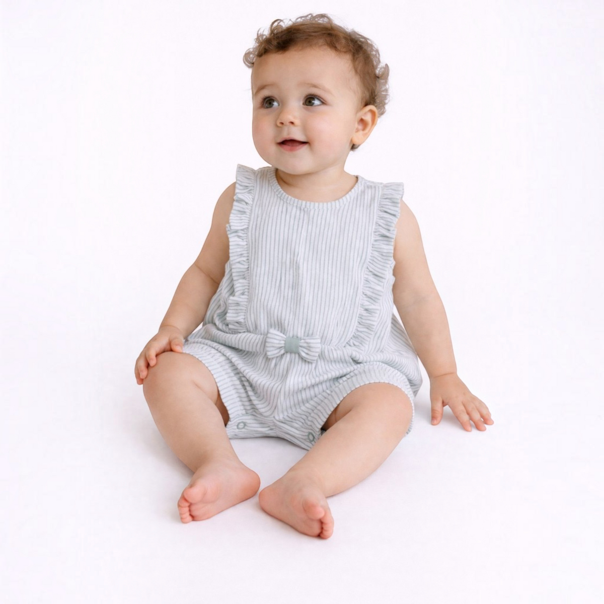 Baby girl wearing a victor and jane light grey striped cotton romper with ruffled shoulders and a small front bow