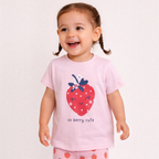A toddler girl wearing a victor and jane light pink t-shirt with a strawberry graphic and matching strawberry leggings