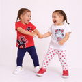 Two girls wearing victor and jane graphic shirt sets with floral and character prints, red and white cotton tops.