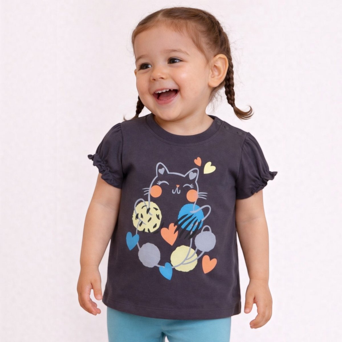 Toddler girl wearing a charcoal grey victor and jane graphic t-shirt with a cat and yarn ball print and ruffled sleeves