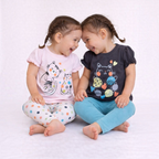 Two girls wearing victor and jane graphic cat shirts and colorful leggings, laughing together on a white background.