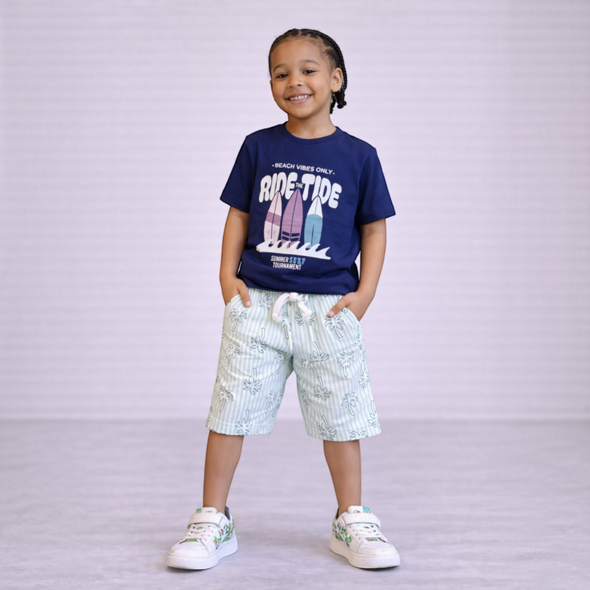 victor and jane boys graphic t-shirt with surf print and striped palm tree shorts on a smiling young boy