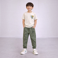 A young boy wearing a victor and jane cream graphic t-shirt and olive green joggers with matching text prints.