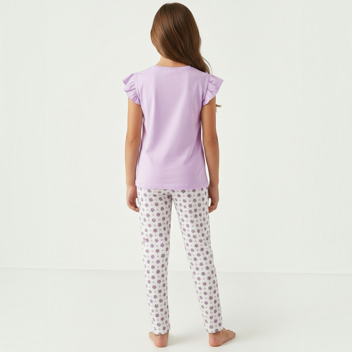 Back view of a girl wearing a victor and jane lavender pyjama set with ruffled sleeves and floral print leggings.