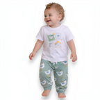 A smiling toddler wearing a victor and jane white graphic t-shirt with a travel-themed print and seagull print pants.