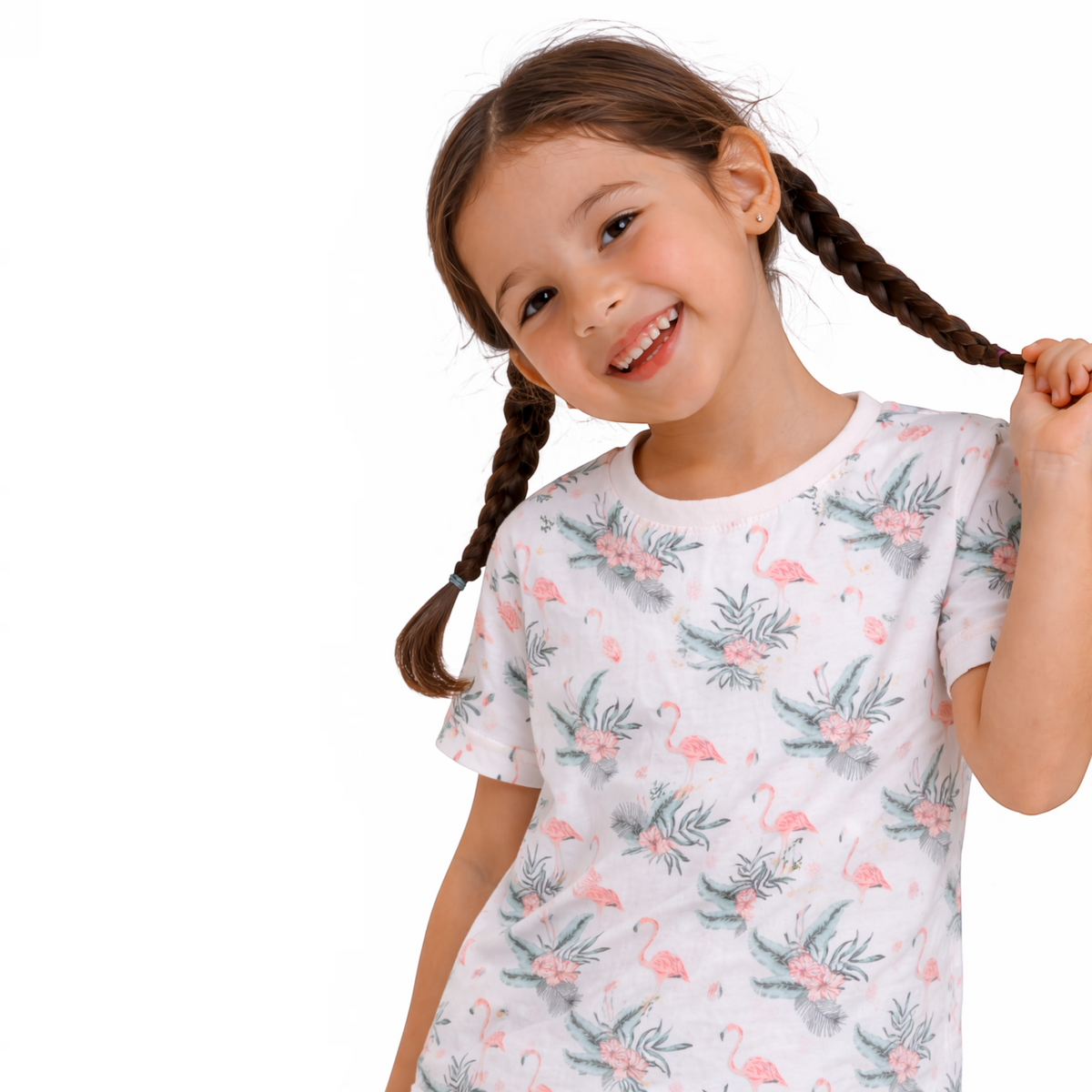 A smiling girl with braided hair wearing a white victor and jane t-shirt featuring a pink flamingo and floral print.