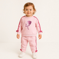 Toddler girl wearing a victor and jane light pink two-piece set with a rose graphic, side stripes, and bow details.