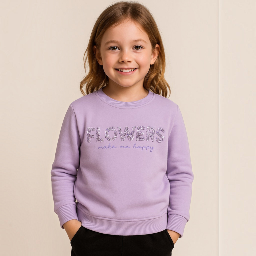 Young girl wearing a light purple victor and jane sweatshirt with sequined FLOWERS text and embroidered detail.