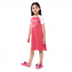 Young girl wearing a victor and jane pink and white short-sleeve pajama dress with a heart graphic and plush slippers