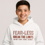 A smiling boy wearing a white victor and jane hooded sweatshirt with Fear-Less Break The Limits graphic print.